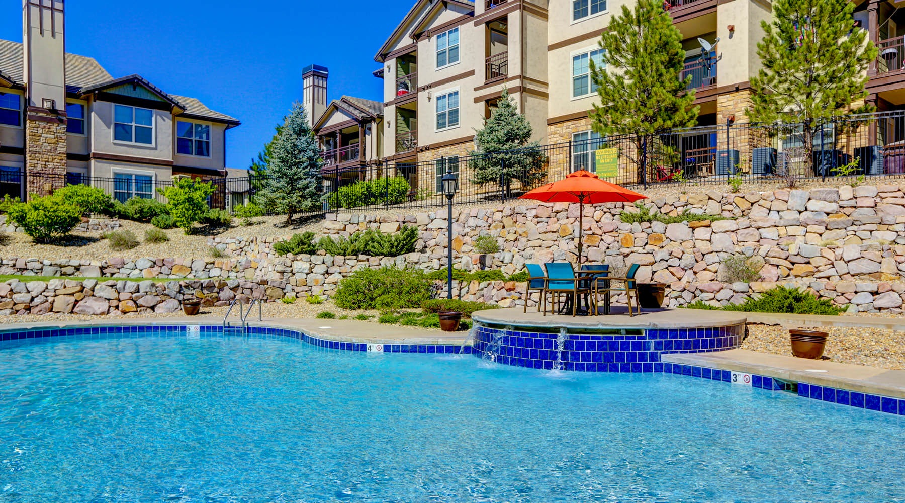 a pool with chairs and umbrellas by a building