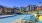 a pool with lounge chairs and umbrellas by a building