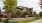 a house with a stone wall and trees in front of it